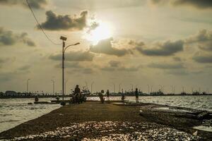 jepara, zentral Java, April 7, 2024 -Fischer beim das Jepara Seebrücke mit ein Sonnenuntergang Himmel wie das Hintergrund mit kostenlos Raum zum Fotokopien. Natur Konzept zum Werbung. foto