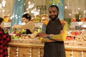 Bauern Markt Verkäufer Verkauf gesund organisch Produkte Nächster zu Essen Marktplatz Stall. jung Mann mit saisonal örtlich gewachsen Gemüse und frisch natürlich Früchte und Gemüse. foto