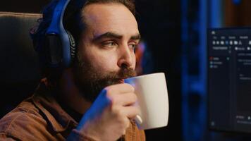 Entwickler Hören Musik- und Trinken Kaffee während tun Programmierung während Fernbedienung Job Verschiebung im Zuhause Büro. es Experte genießen Audio- Podcast und heiß Getränk, Arbeiten auf PC, Kamera ein schließen oben foto