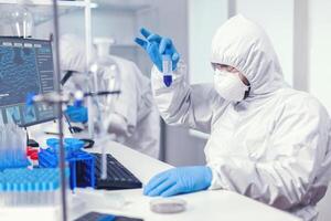 Wissenschaftler im Labor Overall suchen eng beim Stichprobe im Prüfung Tube im das Kurs von Coroanvirus. Forscher im Labor tragen Overall tun Forschung und Analysieren Substanz während global Pandemie mit COVID-19. foto