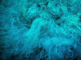 Fischer Hände Nähen Blau Angeln Netze Sitzung auf das Boden und umgeben groß Netz foto