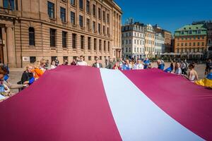 beschwingt Feier im alt Stadt, riga groß lettisch Flagge gehaltenen hoch durch Menge foto