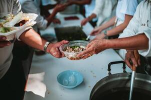 Fütterung Konzepte . Hand angeboten zu spenden Essen von ein Reich Mann Aktie. das Konzept von Sozial Teilen . Arm Menschen Empfang Essen von Spenden foto