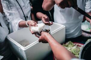 Fütterung Konzepte . Hand angeboten zu spenden Essen von ein Reich Mann Aktie. das Konzept von Sozial Teilen . Arm Menschen Empfang Essen von Spenden foto