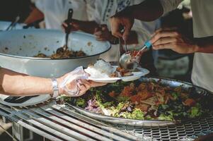 Freiwillige sind Portion zu geben kostenlos Essen zu das hungrig obdachlos. Essen Bedienung und Essen Spende Konzept foto