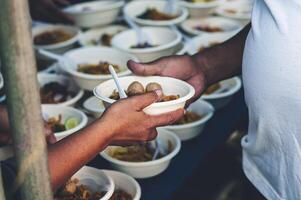 Freiwillige Portion heiß Mahlzeiten zu hungrig Migranten humanitär Hilfe Konzept. foto