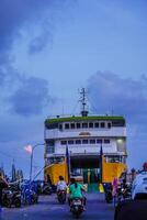 Jepara zentral Java, April 7, 2024 - - Rückseite Aussicht von ein zwischen den Inseln Kreuzung Schiff gegen das Hintergrund von das Abend Himmel mit kostenlos Raum zum Fotokopieren. Vorderseite Aussicht von das Schiff angedockt beim das Jepara foto