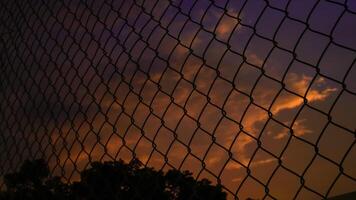 Schuss von das Eisen Netz Zaun gegen das Hintergrund von ein Orange Himmel im das Nachmittag. foto