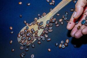 schwarz Kaffee Bohnen sind gesehen schließen oben mit ein hölzern Löffel auf ein schwarz Tuch. foto