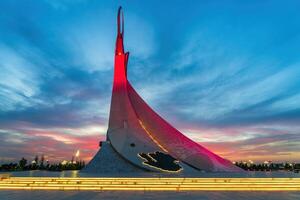 Usbekistan, Taschkent - - September 15, 2023 Monument von Unabhängigkeit im das bilden von ein Stele mit ein Humo Vogel auf ein Dämmerung mit dramatisch Klötze im das Neu Usbekistan Park. foto