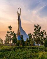 Usbekistan, Taschkent - - September 15, 2023 Monument von Unabhängigkeit im das bilden von ein Stele mit ein Humo Vogel auf ein Dämmerung mit dramatisch Klötze im das Neu Usbekistan Park. foto