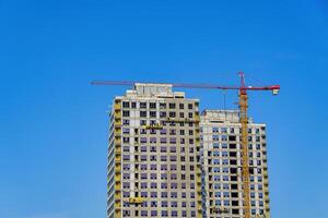 ein Kran Gebäude ein Wolkenkratzer gegen ein Blau Himmel. foto
