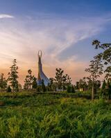 Usbekistan, Taschkent - - September 15, 2023 Monument von Unabhängigkeit im das bilden von ein Stele mit ein Humo Vogel auf ein Dämmerung mit dramatisch Klötze im das Neu Usbekistan Park. foto