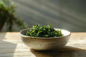 ein Teller mit Grün Salat gemacht von Chukka Seetang auf ein hölzern Tisch, beleuchtet durch hell Sonnenlicht. vegan Meeresfrüchte. foto