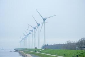 Wind Turbinen im ein Reihe auf das Küste im das Nebel und Nebel foto