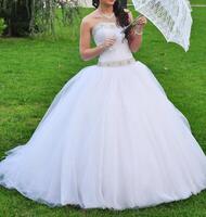 Nahansicht Porträt von jung schön Braut im ein Hochzeit Kleid Stehen auf ein Grün Feld und halten ein Weiß Regenschirm foto