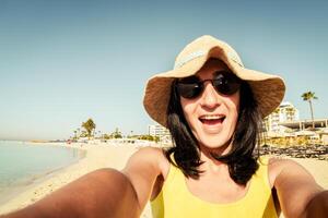 glücklich Brünette Frau Tourist aufgeregt nehmen Selfie Pose beim Strand auf Ferien Show Frieden Finger Symbol - - tausendjährig Mädchen haben Spaß lächelnd beim Kamera - - Menschen und Ferien Konzept foto