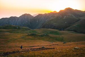 Wanderer Backpacker auf schwarz Felsen Weg im lagodekhi gehen auf Weg Weg mit dramatisch Sonnenuntergang Über Berg Angebot foto