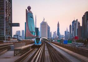 Dubai, VAE - - 10 .. Oktober, 2022 - - Metro kommt an zu Metro halt im Stadt von Dubai mit szenisch modern Gebäude Panorama Hintergrund foto