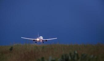 Nacht Flug. das Flugzeug landet auf das Runway. Staub. dunkel Himmel. Kopieren Raum. Flüge foto