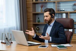 reifen Geschäftsmann mit Headset beschäftigt, verlobt im ein online Konferenz Anruf während Arbeiten entfernt von ein Zuhause Büro aufstellen. foto