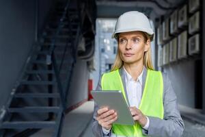 ernst zuversichtlich Denken weiblich Ingenieur mit Tablette Computer inspizieren Fabrik tragen schwer Hut und reflektierend Weste. foto