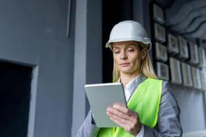 ernst zuversichtlich Denken weiblich Ingenieur mit Tablette Computer inspizieren Fabrik tragen schwer Hut und reflektierend Weste. foto