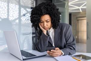 afrikanisch amerikanisch Geschäftsfrau empfangen Schlecht Nachrichten Nachrichten Botschaft auf Telefon, verärgert lesen mit App auf Smartphone, Boss unzufrieden und traurig beim Arbeitsplatz Innerhalb Büro. foto