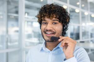 ein heiter Kunde Bedienung Vertreter tragen ein Headset im ein zeitgenössisch Büro Umfeld. seine freundlich Haltung schlägt vor Zugänglichkeit und Professionalität. foto