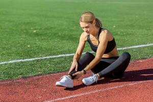 sportlich Frau im Sportbekleidung halten ihr Knöchel im Schmerzen auf ein hell sonnig Tag beim das Laufen Schiene, abbilden Sport Verletzung. foto