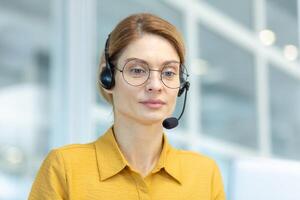 ernst Denken Geschäftsfrau schließen oben Innerhalb Büro, weiblich Arbeiter mit Headset hört zu zu Konversation und hilft Klient, online Treffen Anruf schließen hoch. foto