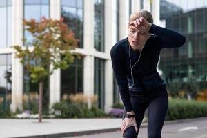 müde Athlet Läufer Atmung schwer, ruhen nach lange laufen, Senior reifen Frau aktiv Lebensstil, Joggen und Fitness in der Nähe von Park, Bäume mit Telefon und Kopfhörer Hören zu Musik- , Podcasts. foto