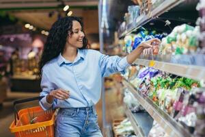 ein spanisch Frau kauft ein Kirsche Tomaten im ein Supermarkt. sie steht mit ein Korb zum Lebensmittel foto