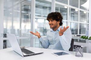 verärgert jung Geschäftsmann Arbeiten Innerhalb Büro mit Laptop, Mann scheitert zu Komplett technisch Projekt auf Zeit, spanisch Mann frustriert Sitzung beim Schreibtisch. foto