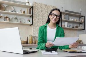 glücklich und erfolgreich Geschäft Frau Arbeiten beim Zuhause im Küche, suchen beim Kamera foto