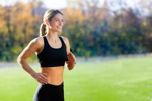 weiblich Athlet ist Laufen im das Stadion auf ein sonnig Tag, Frau im Sportbekleidung ist aktiv. foto