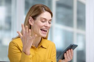 froh erfolgreich Geschäft Frau feiern Sieg Erfolg, Frau Boss empfangen online Benachrichtigung auf Telefon, Financier Innerhalb Büro beim Arbeitsplatz, mit App auf Smartphone. foto