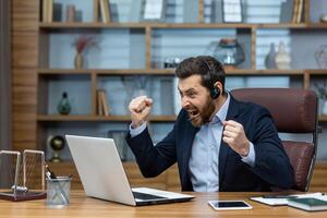 energisch männlich Unternehmer im Zuhause Büro mit Headset, ausdrücken Sieg und Erfolg mit ein Faust Pumpe. foto