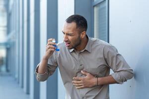 ein Attacke von Asthma, Allergien. ein jung Mann mit ein Inhalator, hat Truhe Schmerzen und Kürze von Atem foto
