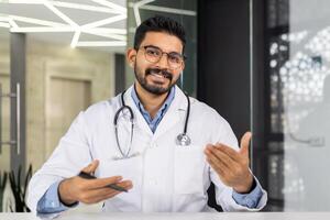 ein Arzt ist lächelnd und halten ein Zwischenablage. er ist tragen ein Weiß Labor Mantel und Brille. das Zwischenablage hat ein Stift auf es foto
