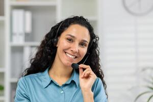 ein heiter Frau mit ein Headset einnehmend im ein freundlich Forderung, suchen direkt beim das Kamera, möglicherweise Bereitstellung Kunde Unterstützung oder virtuell Hilfe von ein Büro. foto