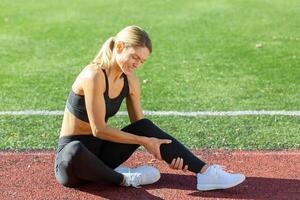 Fitness Enthusiast Gefühl Beschwerden im ihr Bein auf das Spur Feld, Anzeige ein Potenzial Verletzung oder Beanspruchung. foto