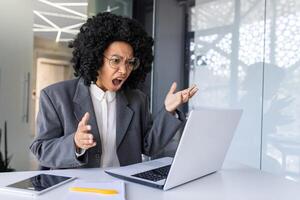 schockiert jung afrikanisch amerikanisch Geschäft Frau traurig suchen beim Laptop Bildschirm auf Tabelle und werfen Hände im Frustration. foto