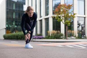 sportlich Frau im Schmerzen halten ihr Schienbein, zeigen Zeichen von Verletzung während Joggen im ein städtisch Umfeld. foto