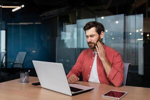 Büro Arbeiter hat ein Zahnschmerzen, ein krank Geschäftsmann funktioniert Innerhalb das Büro mit ein Laptop, ein Mann hat ein Zahnschmerzen beim das Arbeitsplatz. foto