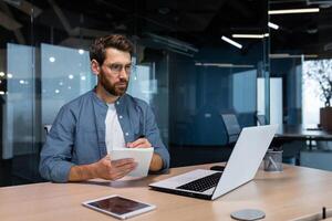 ernst Geschäftsmann ist Schreiben Nieder Information studieren online während Sitzung Innerhalb das Büro. foto