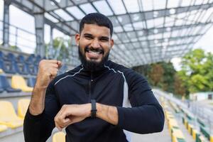 ein sportlich Mann im Sportbekleidung steht bereit und bereit im ein leeren Stadion, verkörpern Entschlossenheit und Fitness. foto