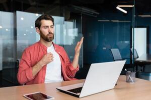 es ist heiß im das Büro, ein Geschäftsmann im ein rot Hemd ist heiß, das Luft Conditioner ist nicht Arbeiten, versuchen zu cool runter, ein Mann Innerhalb das Büro ist Arbeiten mit ein Laptop. foto