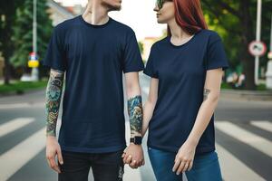 Paar mit Tätowierungen auf ihr Hände tragen ein Marine Blau Rundhalsausschnitt leer Attrappe, Lehrmodell, Simulation T-Shirt mit kurz Ärmel im das Mitte von das Fußgänger Kreuzung foto