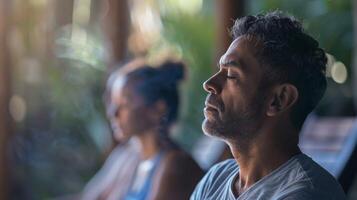 ein Mann ist üben achtsam Atmung Techniken während ein geführt Meditation Session beim seine Wellness Rückzug foto